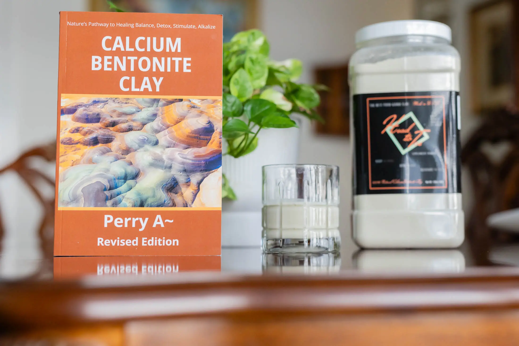 Calcium bentonite clay product with a glass of water and plant in background.